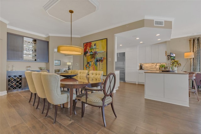 dining area with crown molding and light hardwood / wood-style floors