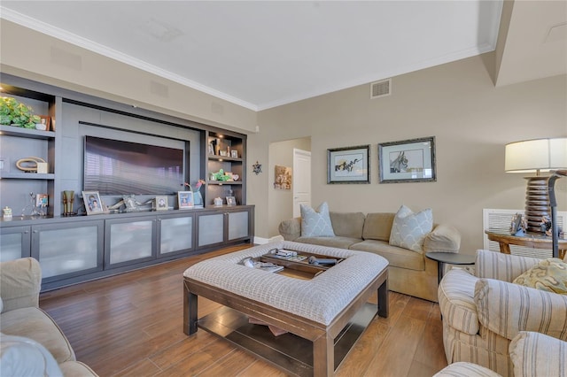 living room featuring crown molding, wood-type flooring, and built in features