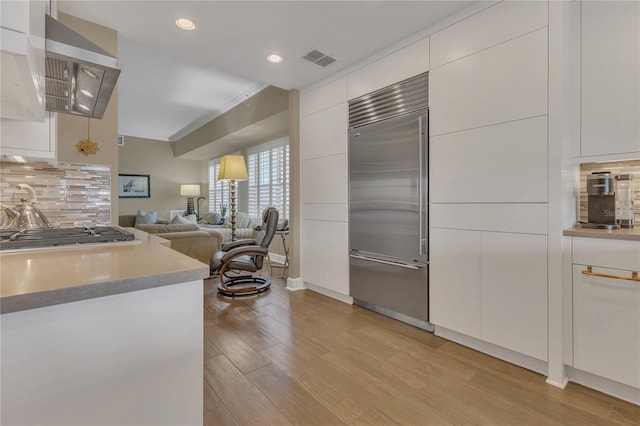 kitchen with white cabinetry, decorative backsplash, light hardwood / wood-style floors, and appliances with stainless steel finishes