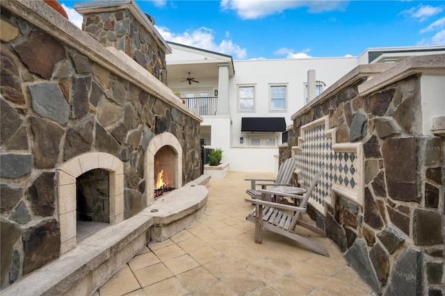 view of patio with ceiling fan and an outdoor stone fireplace