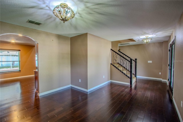 spare room featuring dark wood-type flooring and a textured ceiling