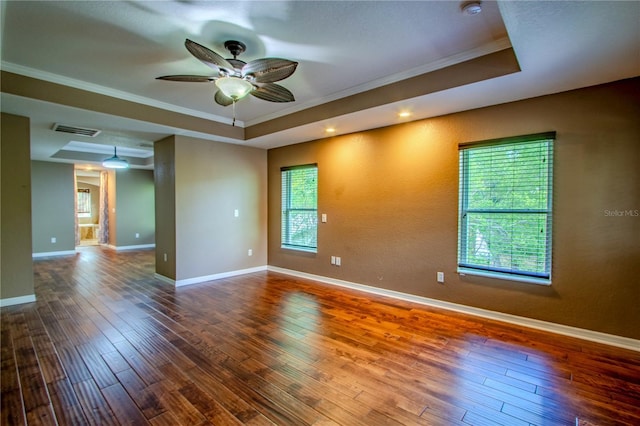 unfurnished room with crown molding, wood-type flooring, a tray ceiling, and a wealth of natural light