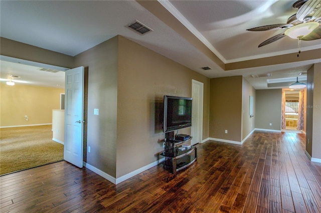 unfurnished living room with a raised ceiling, ornamental molding, dark hardwood / wood-style floors, and ceiling fan