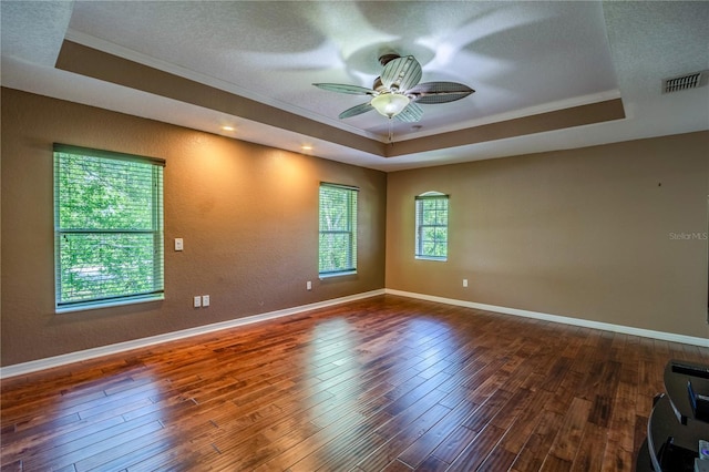 spare room featuring crown molding, ceiling fan, a textured ceiling, dark hardwood / wood-style flooring, and a raised ceiling