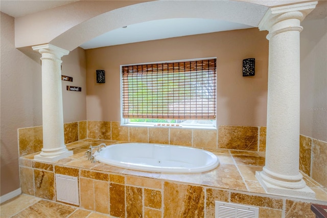 bathroom featuring a relaxing tiled tub and decorative columns