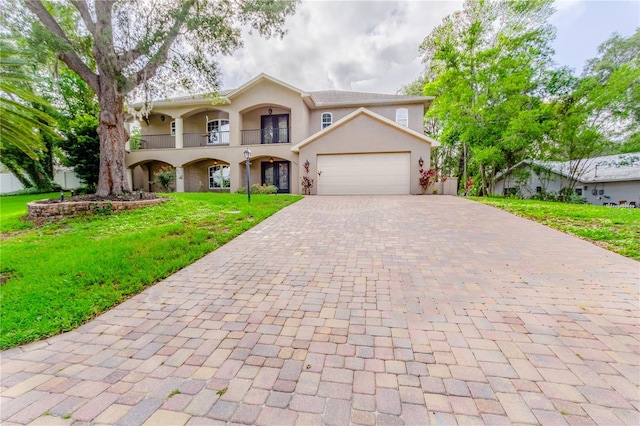 view of property with a balcony, a garage, and a front lawn