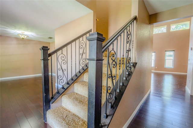 stairway featuring a towering ceiling and wood-type flooring