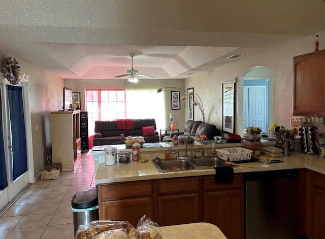 kitchen with sink, a textured ceiling, light tile patterned floors, stainless steel dishwasher, and ceiling fan