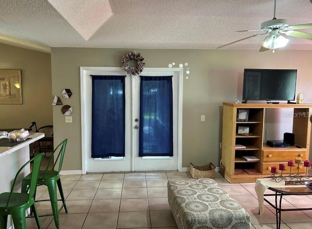 living room with ceiling fan, tile patterned floors, and a textured ceiling