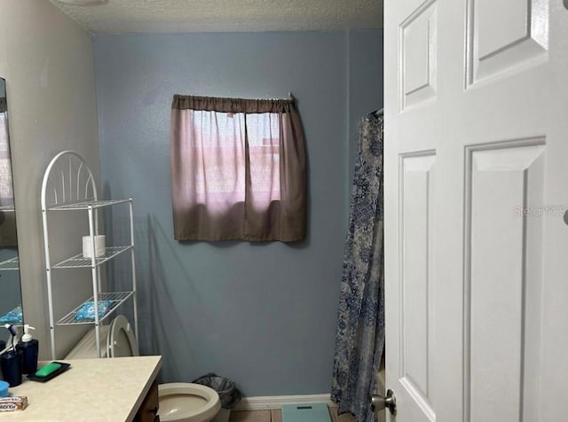 bathroom with vanity, a textured ceiling, tile patterned floors, toilet, and walk in shower