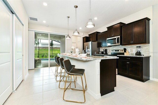 3373 Lilac Way, Davenport, FL 33897 - kitchen with a center island with sink, appliances with stainless steel finishes, pendant lighting, light stone countertops, and backsplash