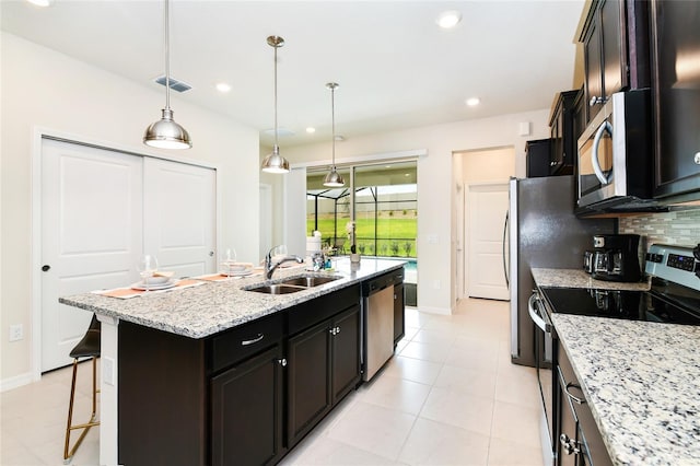 3373 Lilac Way, Davenport, FL 33897 - kitchen featuring a kitchen island with sink, tasteful backsplash, light stone countertops, and appliances with stainless steel finishes