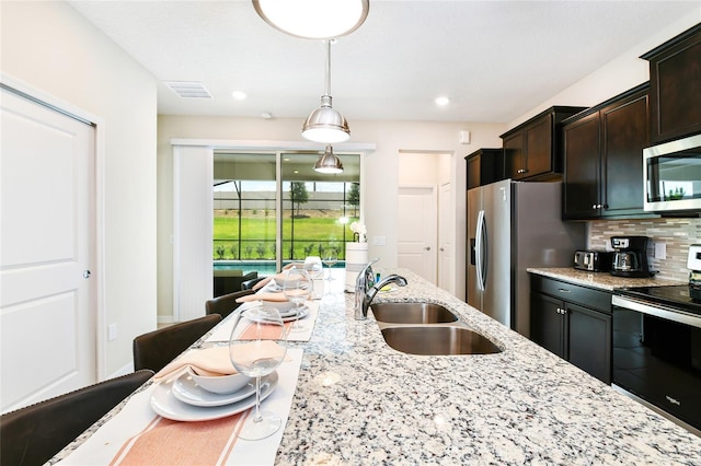 3373 Lilac Way, Davenport, FL 33897 - kitchen featuring sink, appliances with stainless steel finishes, hanging light fixtures, light stone counters, and tasteful backsplash
