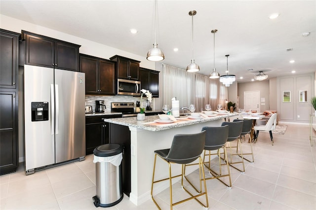 3373 Lilac Way, Davenport, FL 33897 - kitchen with a kitchen bar, hanging light fixtures, light tile patterned floors, stainless steel appliances, and a center island with sink