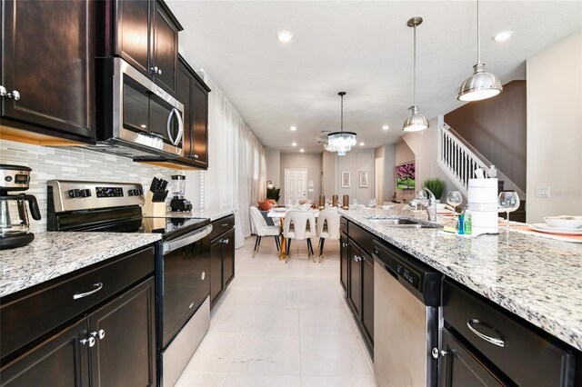 3373 Lilac Way, Davenport, FL 33897 - kitchen featuring dark brown cabinetry, sink, pendant lighting, stainless steel appliances, and decorative backsplash
