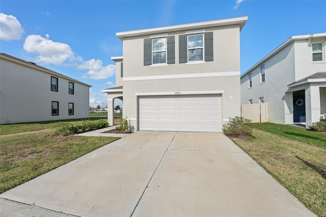 traditional-style home featuring a garage, a front yard, concrete driveway, and stucco siding