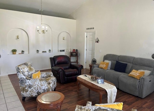 tiled living room featuring an inviting chandelier and high vaulted ceiling