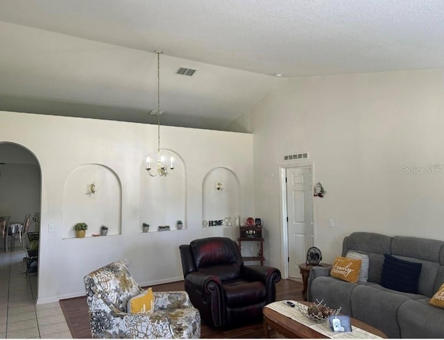 living room with tile patterned flooring, high vaulted ceiling, and an inviting chandelier