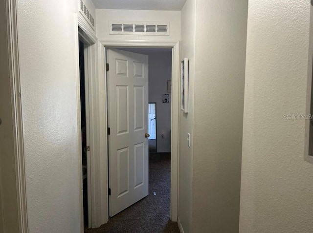 hall featuring dark colored carpet