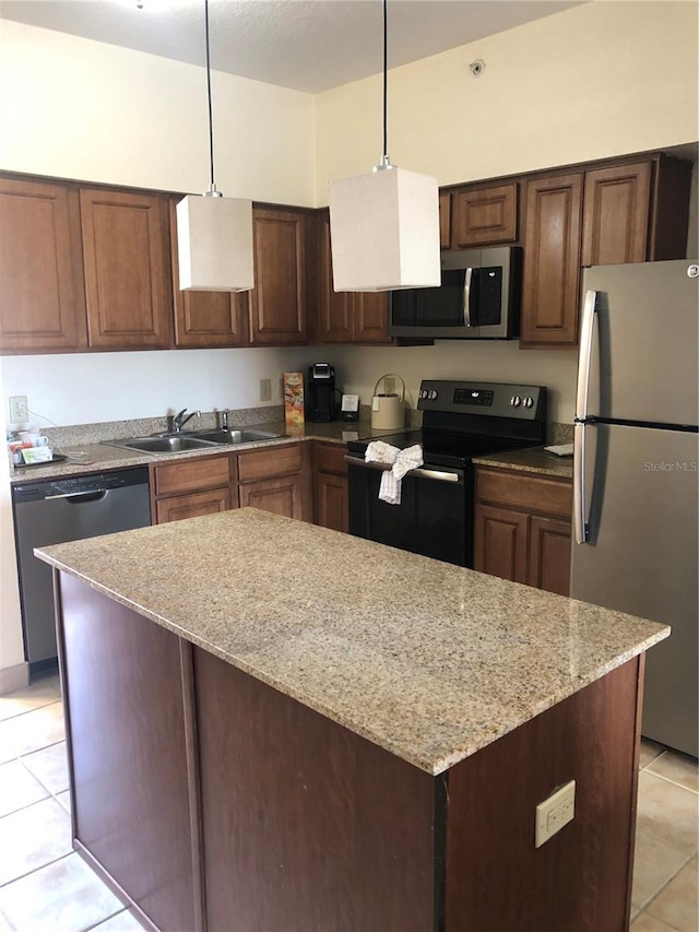 kitchen with appliances with stainless steel finishes, a center island, hanging light fixtures, a sink, and light tile patterned flooring