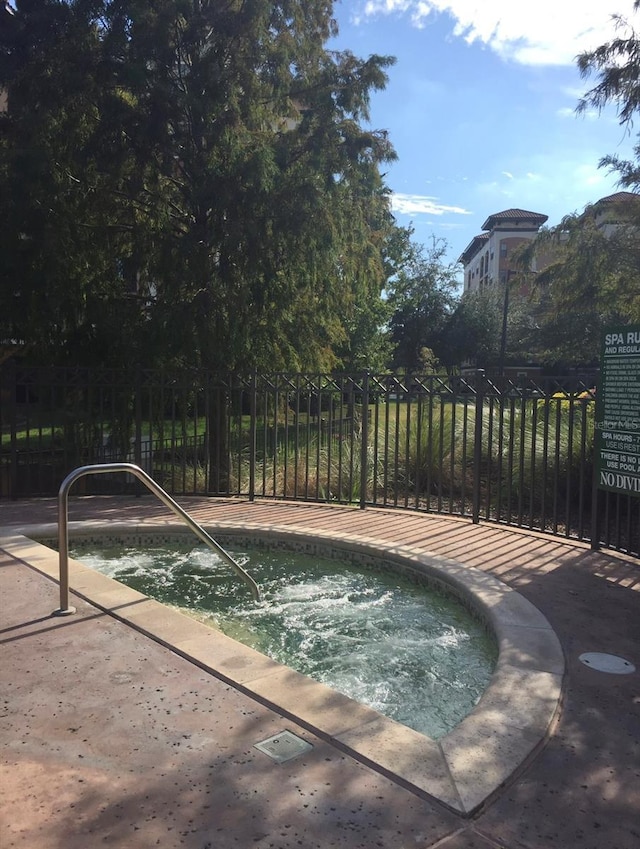 view of pool featuring fence and an in ground hot tub