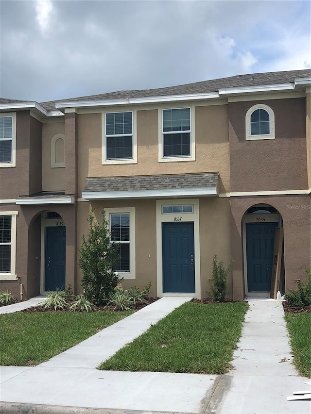 multi unit property with a shingled roof and stucco siding