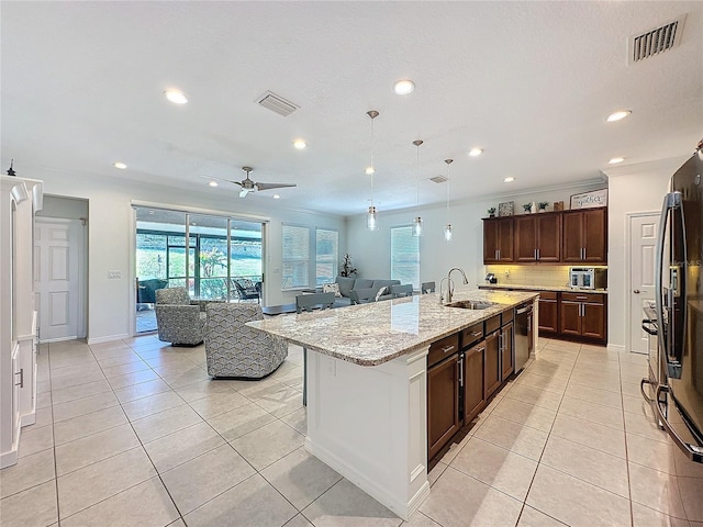 kitchen with a kitchen island with sink, sink, light stone counters, dishwasher, and pendant lighting