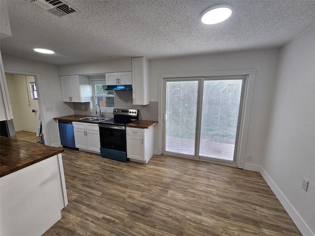 kitchen with dark wood-type flooring, butcher block counters, sink, stainless steel appliances, and white cabinets