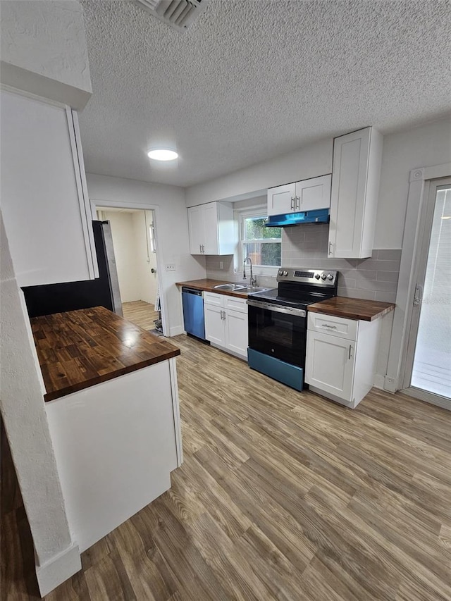 kitchen with stainless steel appliances, white cabinetry, butcher block counters, and light wood-type flooring