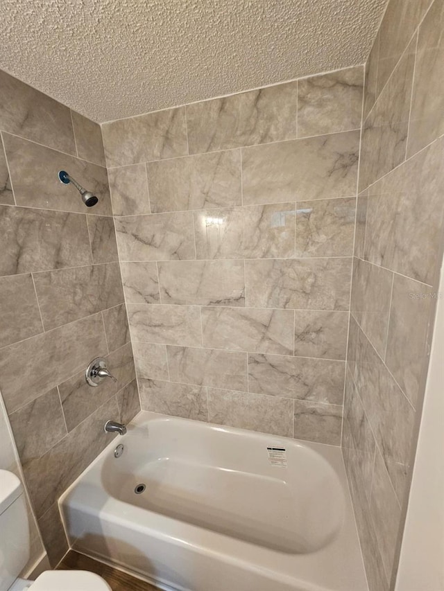 bathroom featuring tiled shower / bath combo and toilet