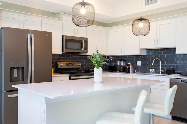 kitchen with white cabinetry, hanging light fixtures, backsplash, and stainless steel appliances