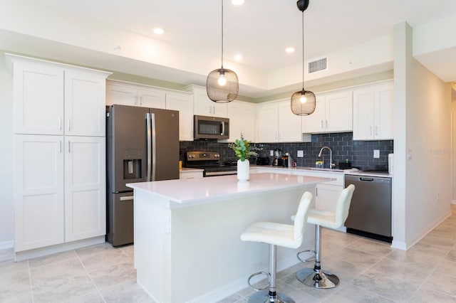 kitchen featuring stainless steel appliances, a center island, decorative backsplash, white cabinets, and decorative light fixtures