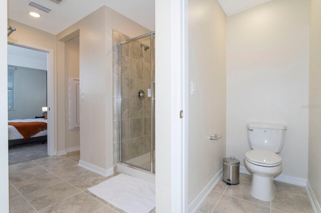 bathroom with a shower with door, tile patterned flooring, and toilet
