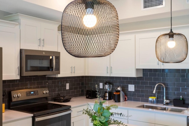 kitchen with sink, white cabinets, backsplash, hanging light fixtures, and stainless steel appliances