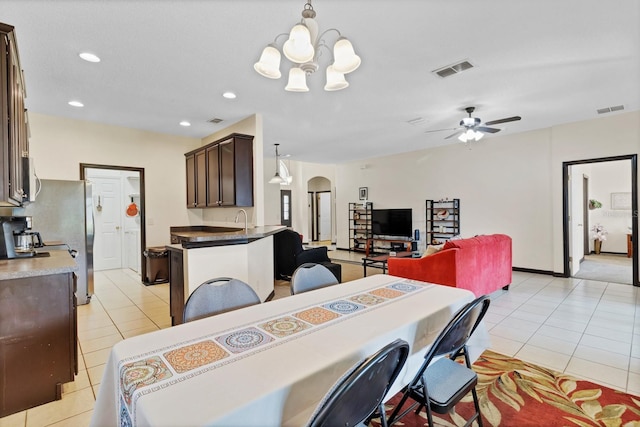 tiled dining room featuring sink and ceiling fan with notable chandelier