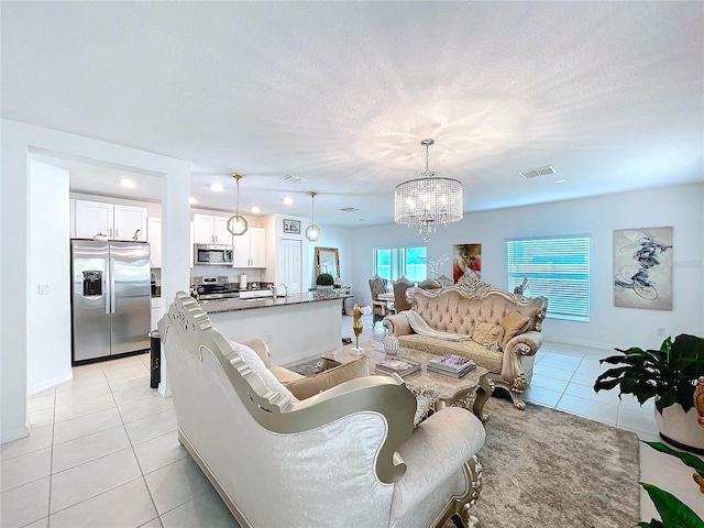 living area featuring visible vents, a textured ceiling, an inviting chandelier, and light tile patterned floors