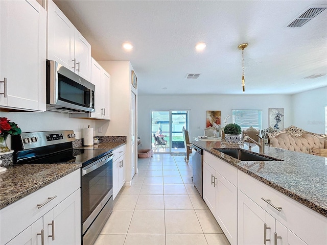 kitchen featuring visible vents, white cabinets, dark stone counters, stainless steel appliances, and a sink