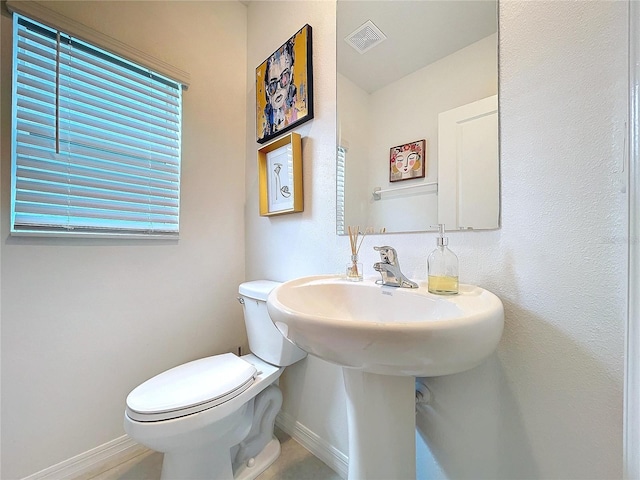 half bathroom with toilet, visible vents, and baseboards