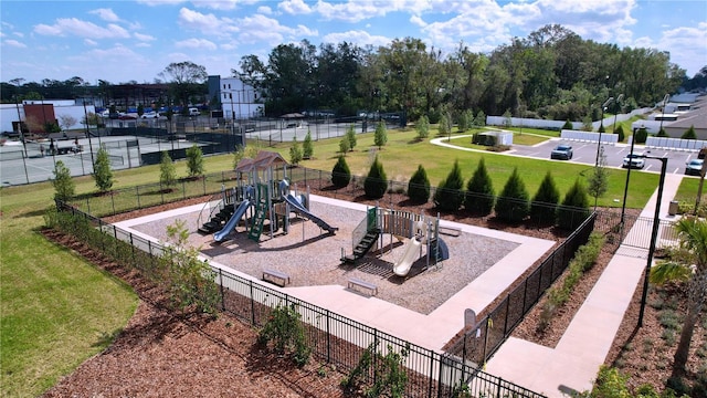 view of home's community with playground community, a lawn, and fence