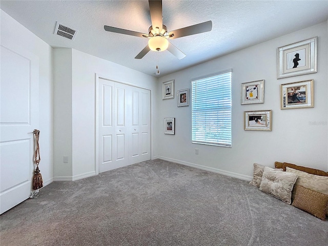 unfurnished bedroom featuring a textured ceiling, a closet, carpet flooring, and visible vents