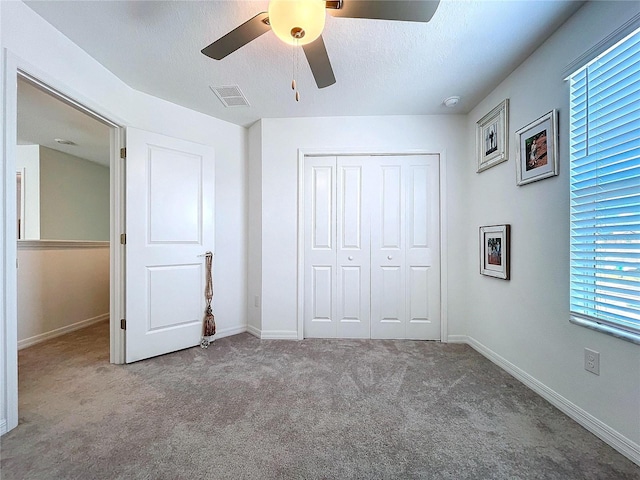 unfurnished bedroom featuring carpet floors, a closet, visible vents, a textured ceiling, and baseboards