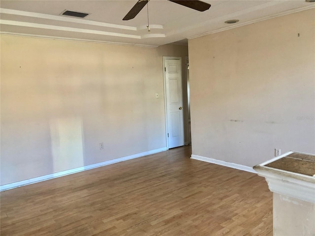 empty room featuring hardwood / wood-style floors, crown molding, a raised ceiling, and ceiling fan