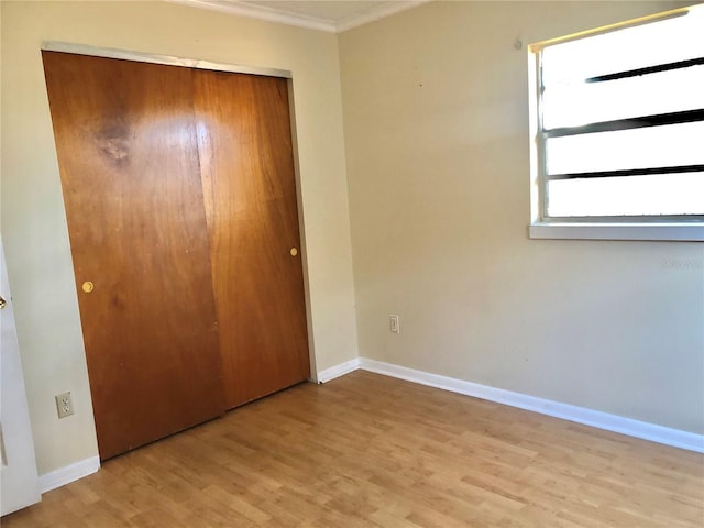 unfurnished bedroom with ornamental molding, light hardwood / wood-style floors, and a closet