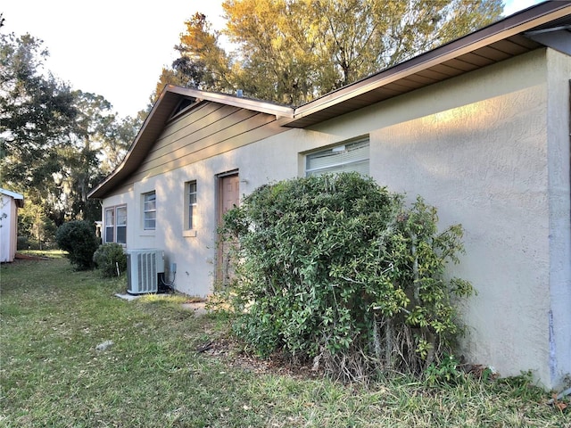 view of side of home with a yard and central AC