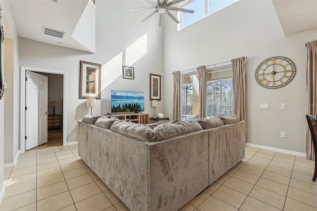 living room featuring a high ceiling, ceiling fan, and light tile patterned floors