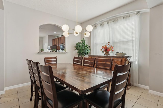 tiled dining room featuring a notable chandelier and a textured ceiling