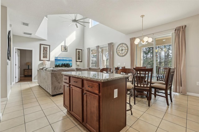 kitchen featuring hanging light fixtures, a breakfast bar, a center island, ceiling fan with notable chandelier, and light tile patterned floors