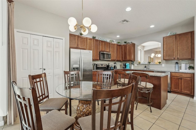 kitchen with a center island, hanging light fixtures, stainless steel appliances, a notable chandelier, and light tile patterned floors