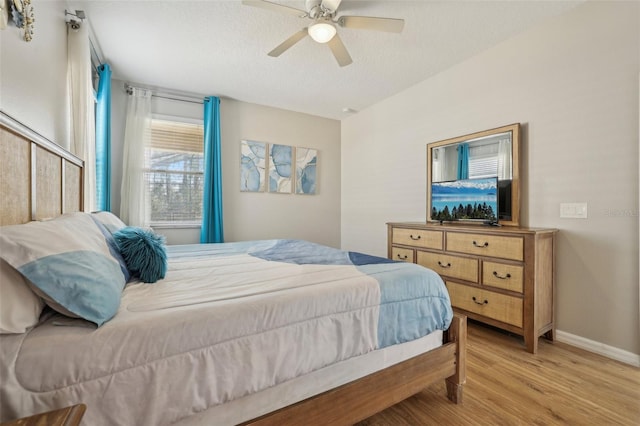 bedroom featuring ceiling fan, light wood-type flooring, and a textured ceiling