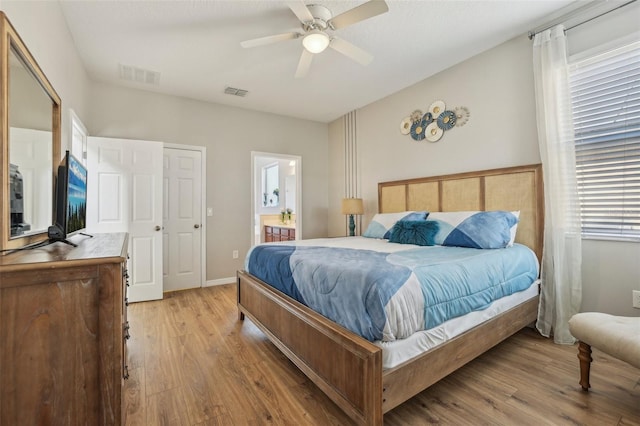 bedroom with ensuite bathroom, light hardwood / wood-style floors, and ceiling fan